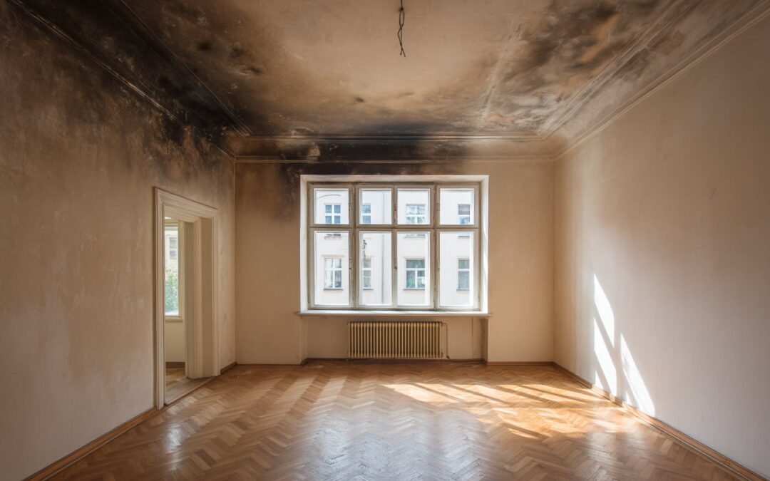 Wohnraum mit deutlichen Rußspuren an Decke und Wänden nach einem Brandschaden.